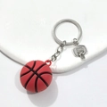Dettaglio di portachiavi basket 3D rosso con ciondolo a canestro in metallo su sfondo bianco - Pallacanestro 3D In Gomma Morbida