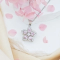 Elegante rotierende Blumen-Halskette mit rosa Zirkonia-Blüten auf weißem Steinuntergrund - Rosa Bauhinie (Silberne Kreuzkette)