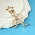 Golden metal bow pendant with star-shaped spring clasp on a minimalist aesthetic background - KC Gold Bowknot Star Buckle