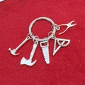 Dettaglio portachiavi in metallo con attrezzi in miniatura su sfondo di feltro rosso - Set Martello Ascia Sega (2#)