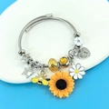 Macro detail of charms featuring sunflowers, bees and daisies on a silver cable bracelet - Silver Open Bangle Style