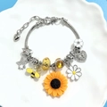 Close-up of DIY charm bracelet with sunflower bee and heart charms on silver snake chain - Silver Snake Chain Style / Small
