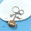 Porte-clés de football américain avec ballon marron et charms de casque en argent poli - Boucle Argentée Avec Casque Athlète Et Football / Style Football 2 en Colle Souple 3D