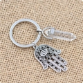 Detail von Hamsa-Hand-Anhänger und weißer Kristall-Säule auf gewebtem Hintergrund - Bergkristall