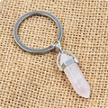 Détail du porte-clés en cristal de quartz rose hexagonal sur fond de toile de jute rustique - Quartz rose