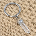 Détail macro du porte-clés pilier en cristal hexagonal naturel sur toile de jute rustique - Cristal blanc