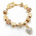 Détail d'un bracelet serpent doré orné d'un pendentif cœur serti de strass brillants - Style Cœur en Strass (2)