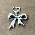 Silver bow pendant with heart-shaped lobster clasp on dark textured background - Silver Bowknot Heart Buckle