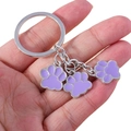 Handheld view of silver keychain with three purple paw print pendants in alloy metal - Purple Dog Paw