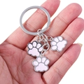Silver alloy keychain with three pink enamel paw charms held in hand on white background - Pink Dog Paw