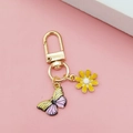 Detail of gold keychain featuring daisy and gradient butterfly on pink background - Yellow Daisy