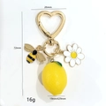 Porte-clés avec marguerite, abeille et citron avec fermoir cœur doré sur fond blanc - Citron En Résine Anneau Cœur