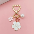 Detail of heart-shaped gold keychain with cherry blossom enamel charms and white pearl - Red and White Bicolor Flower (Heart Buckle)