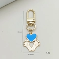 Detailweergave van de gouden sleutelhanger met babyvoetjes en blauwe hartbedel - D-Ring Sluiting Met Hart Voetafdruk