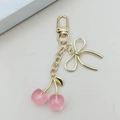 Detail view of pink cherry keychain with gold lobster clasp and delicate ribbon bow - Transparent Pink Cherry [D-Clasp]