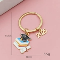 Détail du porte-clés de remise des diplômes 2025 avec breloques dorées et dimensions - Livres Empilés Et Diplôme (2025)