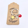 Détail des breloques en émail pomme et fleur sur un porte-clés cœur Thank You - Pack Petite Carte Fleur Jaune
