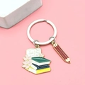 Portachiavi per diploma con libri impilati e ciondolo a matita rossa su fondo rosa - Stile Libri e Matita