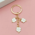 Porte-clés doré avec trois trèfles à quatre feuilles blancs sur fond rose tendre - Blanc