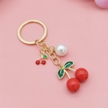 Cute cherry keychain with red fruit charms, green leaves and white pearl on pink surface - Solid Red Round Cherry