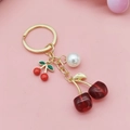 Golden cherry keychain with red resin fruit pendants and white pearl on pink background - Transparent Red Square Cherry
