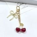 Porte-clés cerise rouge avec fruits translucides et breloque noeud doré sur fond blanc - Cerise (Fermoir en or KC) / Rouge Pailleté