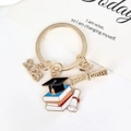 Porte-clés de remise de diplôme 2025 doré avec breloques toque, livre et parchemin - Année de Diplôme et Style Mortier Livre