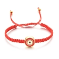 Gros plan du bracelet tressé rouge avec cordon ajustable et breloque dorée mauvais œil - Rouge