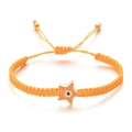 Detail of hand-woven orange cord bracelet featuring a gold star and blue evil eye charm - Orange