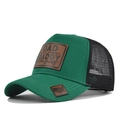 Close-up of leather patch on mesh trucker hat with vintage American flag shield detail - Grass Green