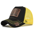 Detail of the lion leather patch and yellow wavy stitching on the black trucker hat - Black with Yellow Mesh