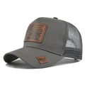 Close-up of charcoal grey trucker hat with brown leather tractor patch and mesh - Dark Gray