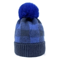 Close-up of blue plaid knit beanie texture and fluffy pom-pom detail on winter hat - Blue