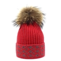 Close-up of red knit beanie featuring a fluffy pompom and sparkly floral cuff pattern - Red