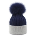 Detail of blue and grey knit beanie showing thick ribbed texture and large fluffy pompom - Navy Blue