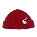 Dettaglio del berretto in maglia rosso scuro con bordi strappati e ciondolo a forma di orso - M / Rosso