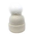 Primer plano de un gorro de punto acanalado blanco con pompón de pelo sintético - Talla única / Blanco