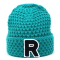 Nahaufnahme einer himmelblauen Strickmütze mit einem schwarz-weißen R-Buchstaben-Patch - Dunkelblau