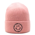 Close-up of pink knit beanie showing ribbed texture and embroidered black smiley logo - Pink