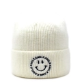 Close-up of smile embroidery on ivory knitted beanie with a soft ribbed texture - White