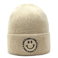 Close-up of the beige ribbed knit beanie featuring a black embroidered smile graphic - Beige