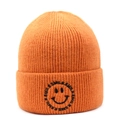 Close-up of orange knitted beanie featuring a black smile face and letter embroidery - Orange