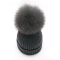 Detail of dark grey knit beanie featuring a fluffy fox fur pom-pom and ribbed texture - Dark Gray