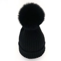 Close-up of black ribbed knit beanie featuring a large fluffy faux fox fur pompom top - Black