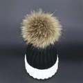 Close-up of black and white knit beanie featuring a large fluffy pom-pom and thick cuff - Black+White