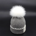 Detail of grey knit beanie with white fluffy fur pom-pom and contrast stitching - Gray