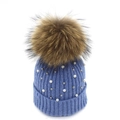 Detail view of dark blue knit hat featuring large faux fur pompom, pearls and metal studs - Blue 1