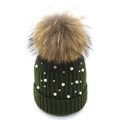 Detailed close-up of dark green knitted hat featuring white pearls and large fur pompom - Dark Green