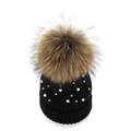 Women's black knit beanie featuring white pearls and a large raccoon fur pompom detail - Black