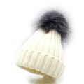 Close-up of knit texture and fluffy dark grey pompom on cream winter beanie hat - Kids / White